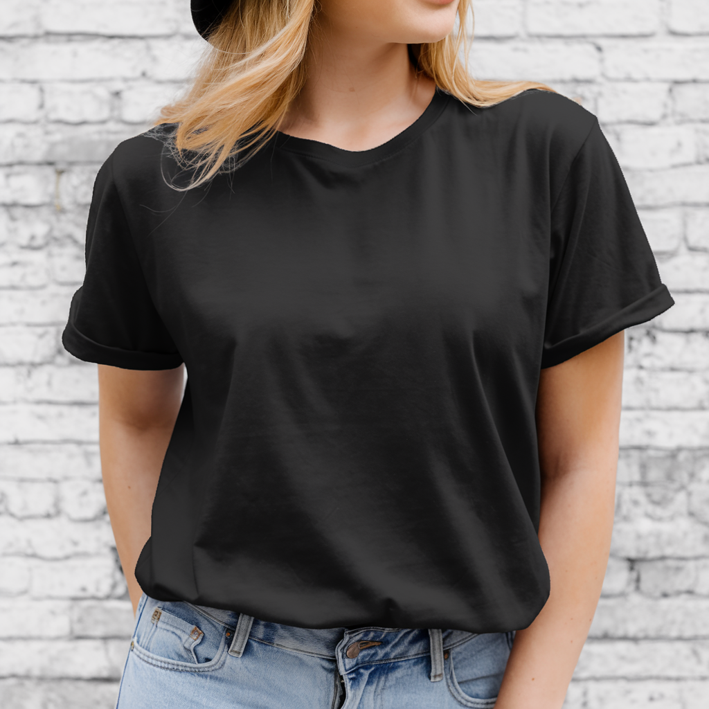 A young woman is poised against a backdrop of a white brick wall. Dressed casually yet chic, she sports a black t-shirt paired seamlessly with classic blue jeans. The woman, with her golden locks cascading from beneath a stylish black hat, gazes thoughtfully to the side. Her expression exudes a sense of calm and relaxed confidence, perfectly portraying a fashionable city-goer enjoying a reflective moment.